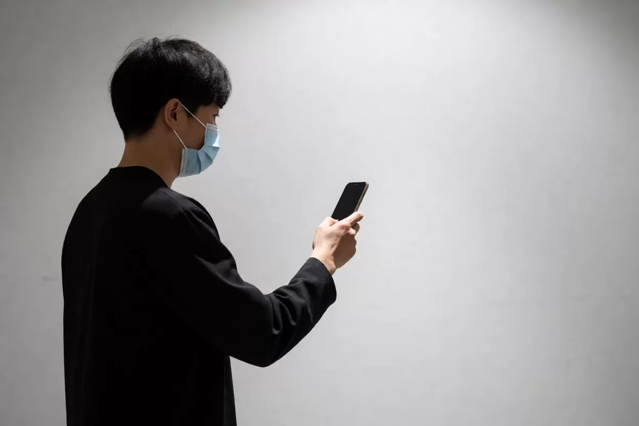 用户在室内戴着口罩使用iPhone面容ID解锁手机的实际场景